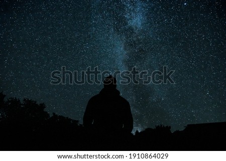 Silhouette of man and a horizon against night sky with milky way, stars and constellations. Monochromatic night picture in wilderness with clear sky. 