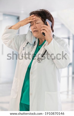 Desperate looking asian female doctor talking on her phone