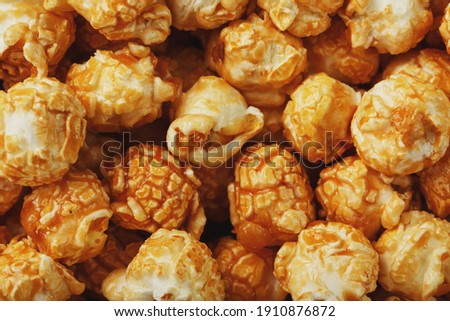 Caramel popcorn close-up as a background, full-screen texture. Admirable praise for watching movies, TV series, cartoons. Close-up, top view