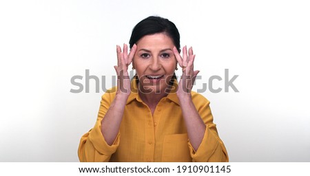 Old woman checking her skin on a white background. The old woman is upset about the problems she sees in her skin. Skin care concept.
