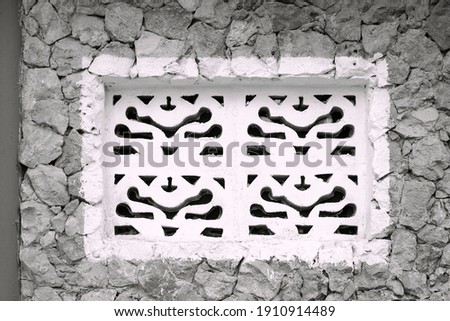 Openwork african window in stone facade, oriental pattern style. Decorative ornate pattern, architectural detail. Black and white photo. Traditional architectural ornamentation. Zanzibar, Tanzania