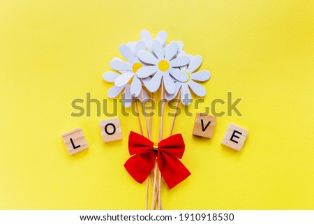 Love made up of wooden cubes with a bouquet of flowers, Valentine's Day. Selective Focus.