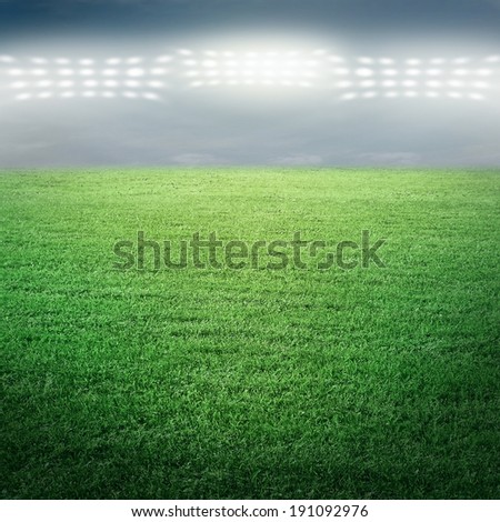 Sport stadium in spotlight with green grass field