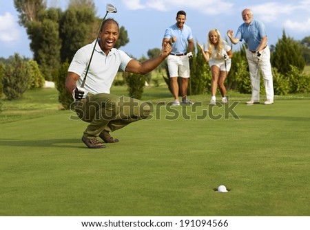 Male golfer and partners happy for successful putt on the green. Royalty-Free Stock Photo #191094566