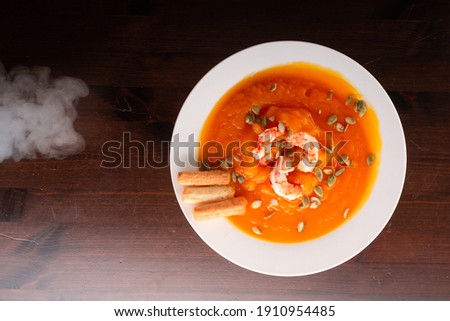 white plate of orange pumpkin soup on the table studio shot 