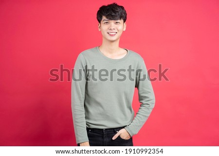 Young man with cheerful expression on a red background