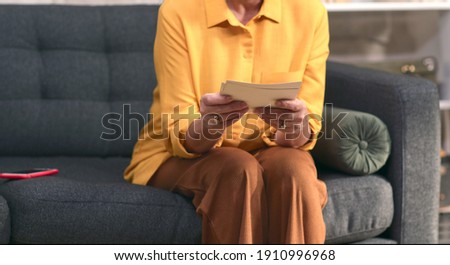 Close-up hands of woman looking at pictures on sofa. Memories concept.