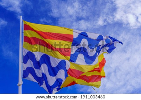 Flag of the city of Badalona, Spain waving on the mast over blue sky