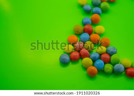 background of many multicolored candies or chocolates in glaze on green background