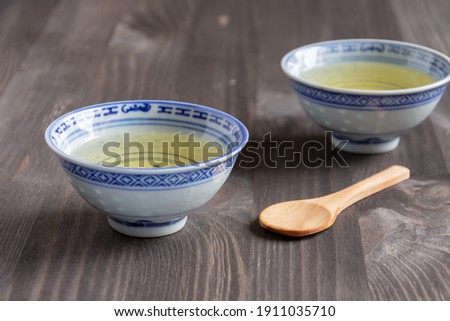 Top view of two blue cups of Chinese tea and wooden spoon, with selective focus, on dark table, horizontal, with copy space