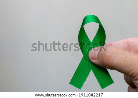 green april. work safety campaign. Man holding a green ribbon. Liver, gallbladder, kidney and lymphoma cancer awareness month concept. Space for text. campaign against abandonment of animals