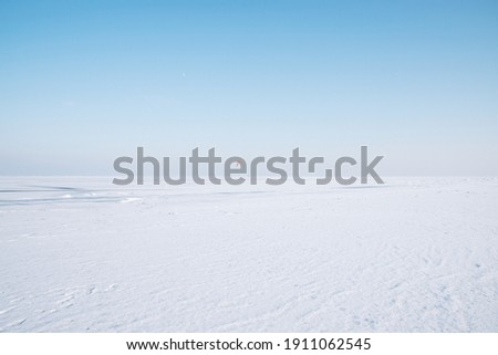 horizon of the frozen sea on the ice a lot of snow blue sky no clouds bright day on the horizon footprints in the snow footpath from people Royalty-Free Stock Photo #1911062545