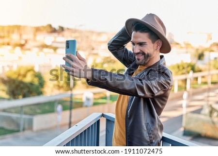 boy taking a selfie with a hat and leather jacket