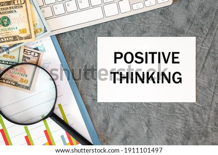 Positive Thinking is written in a document on the office desk with office accessories, money, diagram and keyboard