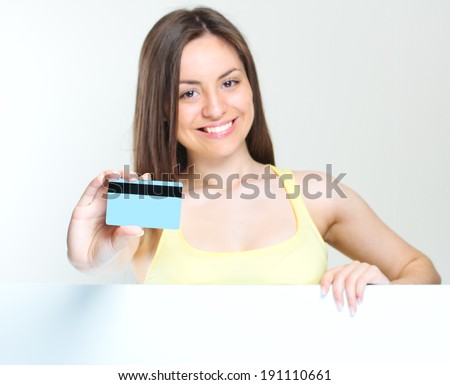 smiling woman holding credit card. big blank poster.