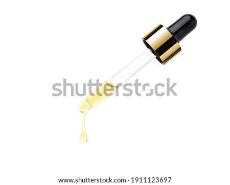 Yellow essential serum oil dripping from gold dropper  isolated on white background. Clipping path. Royalty-Free Stock Photo #1911123697