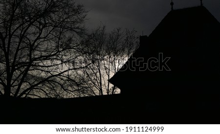 The sun sets in the courtyard of a medieval castle and bathes the world in a dark and eerie mood