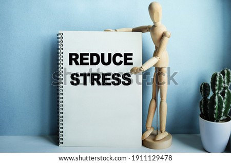 Wooden man next to a notebook, the inscription on the notebook has a financial or marketing concept. The inscription in the notebook STORY - REDUCE STRESS.