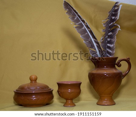 two feathers from the eagle lie on a yellow background and cup and bowl 