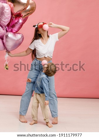 Young people dancing, smiling and having fun near  big branch of pink heart-shaped ballons. Isolated on pink background.