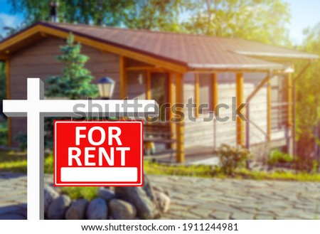 Investment or business in  field of rental property. For rent sign as symbol of business in rental property. Rental business. Blurred country house in background. Investment in renting country house