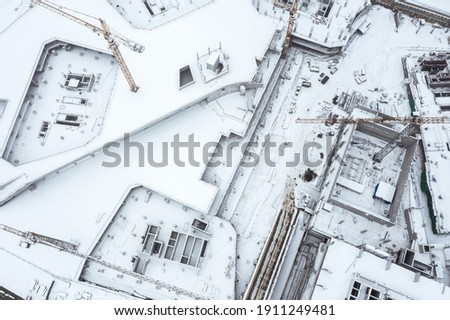 aerial top view of large construction site with cranes covered with snow