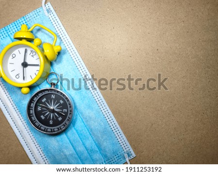 Selective focus.Clock,face mask and compass on a wooden background.Shot were noise and film grain.