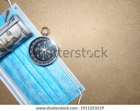 Selective focus.Dollar banknote,face mask and compass on a wooden background.Shot were noise and film grain.