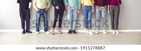 Your shoes says a lot about you. Cropped image of the legs of people in ordinary clothes and shoes standing in a row near the wall. Concept of diverse people in modern business. Royalty-Free Stock Photo #1911278887