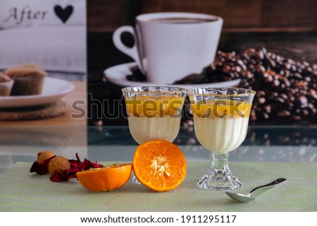 Magnolia presentation accompanied by tangerine and ornaments. Mandarin cup, multi-colored fruit pudding. Royalty-Free Stock Photo #1911295117