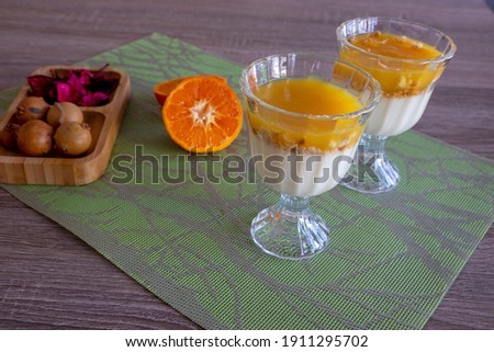 Magnolia presentation accompanied by tangerine and ornaments. Mandarin cup, multi-colored fruit pudding.