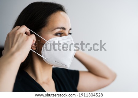 Woman Putting On Medical FFP2 Face Mask Royalty-Free Stock Photo #1911304528