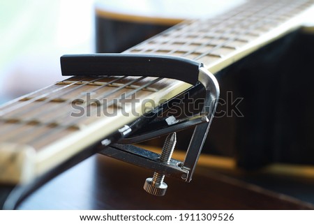 An acoustic guitar for artist playing a stringed musical instrument on stage. Black guitar with a capo. Musical background.