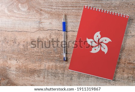 Notepad with Hong Kong flag, pen on wooden background, study concept