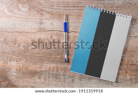 Notepad with Estonia flag, pen on wooden background, study concept