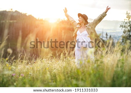Portrait happy woman enjoying sunset stay on the green grass on the forest peak of mountain. Fresh air, Travel, Summer, Fall, Holidays, Journey, Trip, Lifestyle.