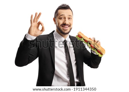 Businessman holding a sandwich in a baguette and gesturing ok sign isolated on white background