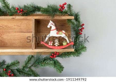Christmas decoration from a wooden shelf, green branches of fir and pine, mistletoe, pine cone and wooden toy horse