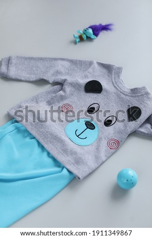 Grey background with clothes for the newborn, the view above. The location of children’s clothes in the background.