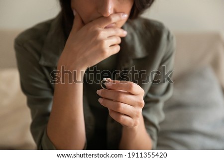 Crop close up of upset woman hold wedding ring think of marriage dissolution or divorce having family problems. Unhappy sad female stressed with relationships end or breakup. Relations, love concept. Royalty-Free Stock Photo #1911355420
