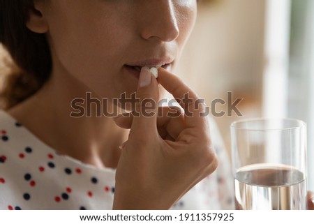 Crop close up of woman feel unhealthy unwell take pill or medication from headache or migraine. Sick female drink antibiotic medicines or drugs struggle with health problems. Healthcare concept. Royalty-Free Stock Photo #1911357925