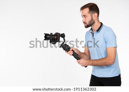 Videographer on a light background. Man holds a camera on stabilizer. Concept - shooting video with professional camera. Videographer career. Video filming services. Professional shooting equipment.