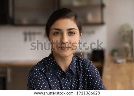 Profile picture of pretty millennial lady of indian ethnicity posing indoors at home in office. Head shot portrait of attractive mixed race woman with stylish makeup looking at camera shoot video blog