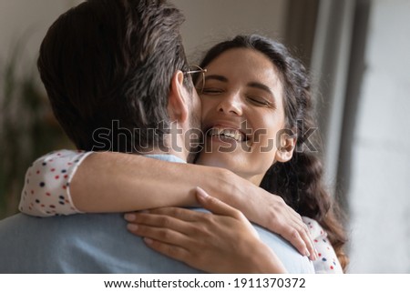 I missed you so much. Excited millennial wife embracing neck of beloved husband meeting at home on return from business trip. Happy young couple cuddling celebrating reunion reconciling after quarrel Royalty-Free Stock Photo #1911370372