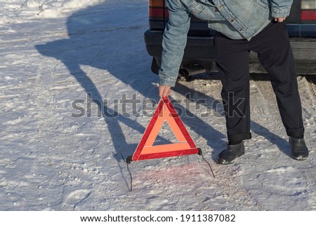 street lighting. white snow. The man puts an emergency sign. Damage to the vehicle.