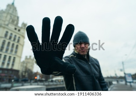 Handsome man in Moscow city center. Cold winter in the Russian capital. 
He extends his hand forward, blocking himself from taking pictures. Sign prohibiting photographing him. Invasion of privacy