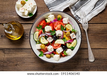 Classic Greek salad with fresh vegetables, feta cheese and  olives. Healthy food. Wooden background. Top view Royalty-Free Stock Photo #1911406540