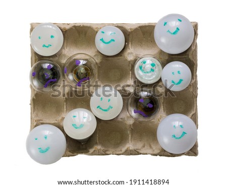 
ecological, power saving lamps of next genetration shown against old ones, placed in eggs' pack cells, isolated
