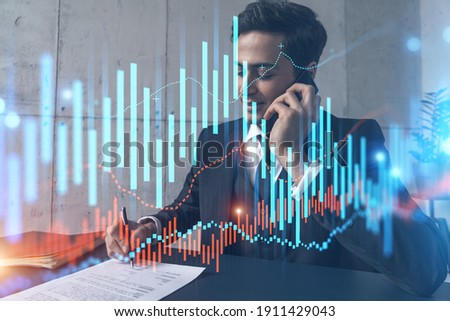 A man in office signing papers while talking phone and stock market graph and chart hologram. Double exposure. Formal wear.