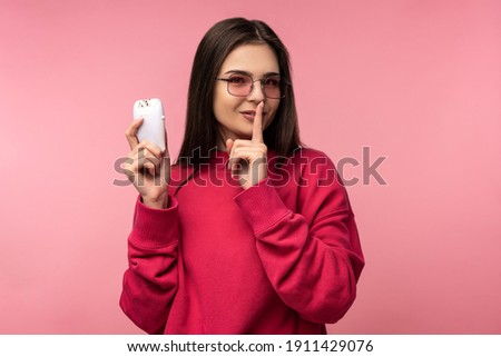 Photo of attractive lady in glasses holds shaving razor, blade. Shows secret. Wears casual pink sweater white pants isolated pink color background